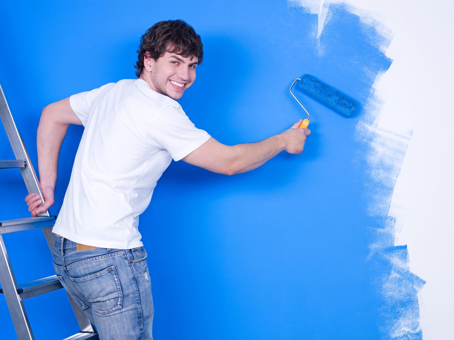 handsome young man with happy smile painting wall